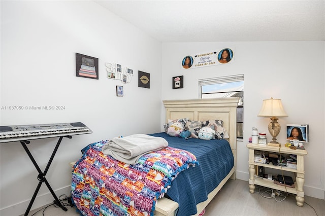 bedroom with lofted ceiling, a textured ceiling, and wood-type flooring