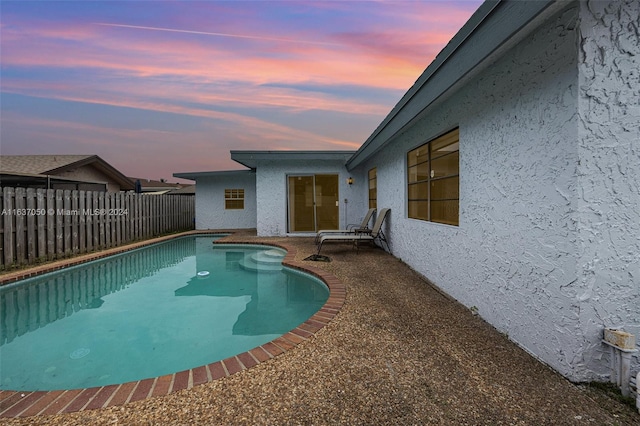 pool at dusk with a patio area