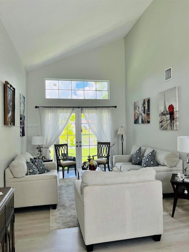 living room featuring light wood-type flooring, high vaulted ceiling, and french doors