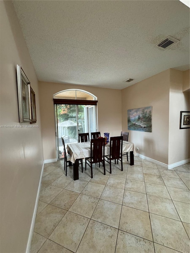 tiled dining room featuring a textured ceiling