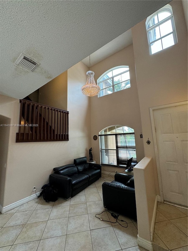 living room with a high ceiling, a textured ceiling, and light tile patterned floors