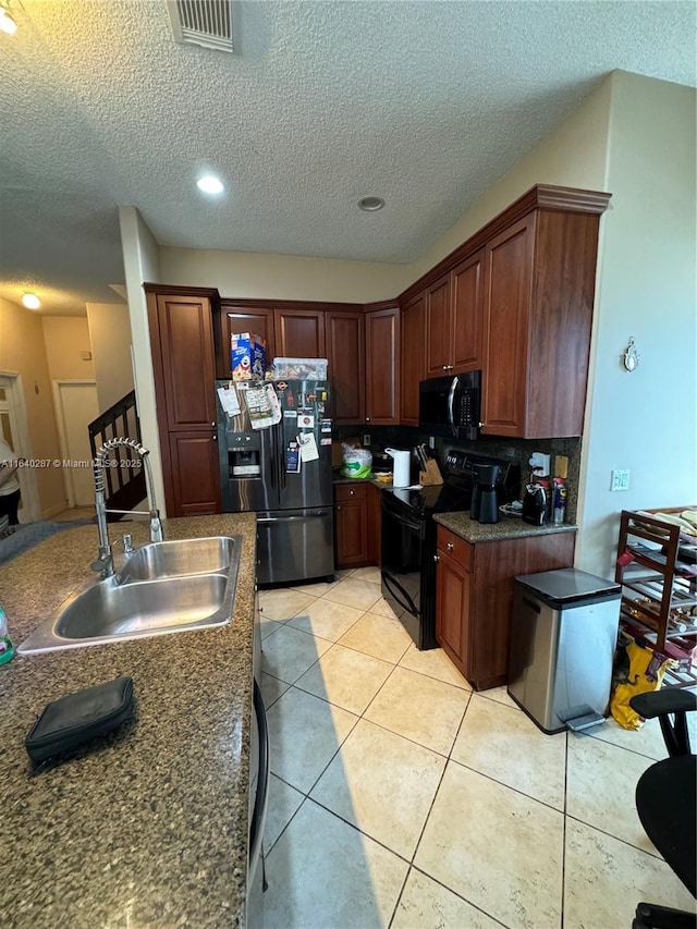 kitchen with sink, light tile patterned floors, a textured ceiling, and black appliances