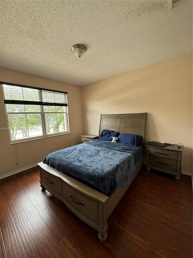 bedroom featuring dark hardwood / wood-style flooring and a textured ceiling