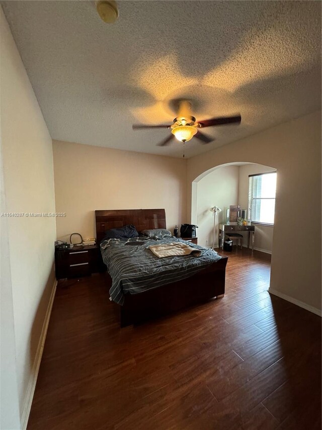 bedroom featuring ceiling fan, a textured ceiling, and dark hardwood / wood-style flooring