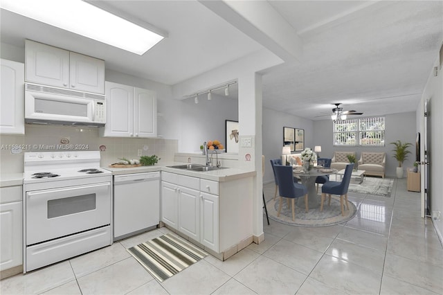 kitchen featuring white appliances, rail lighting, sink, decorative backsplash, and white cabinetry