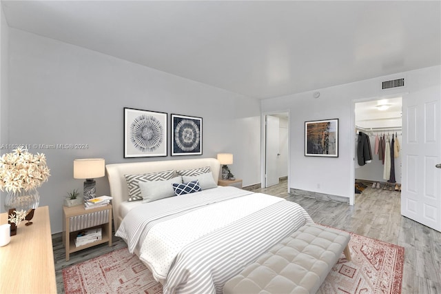 bedroom featuring light wood-type flooring, a walk in closet, and a closet