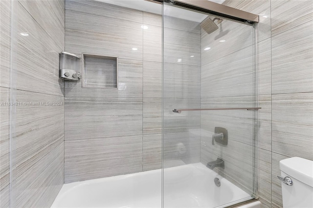 bathroom with combined bath / shower with glass door and toilet