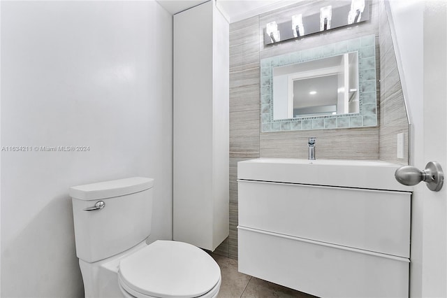 bathroom with tile patterned flooring, vanity, toilet, and tile walls