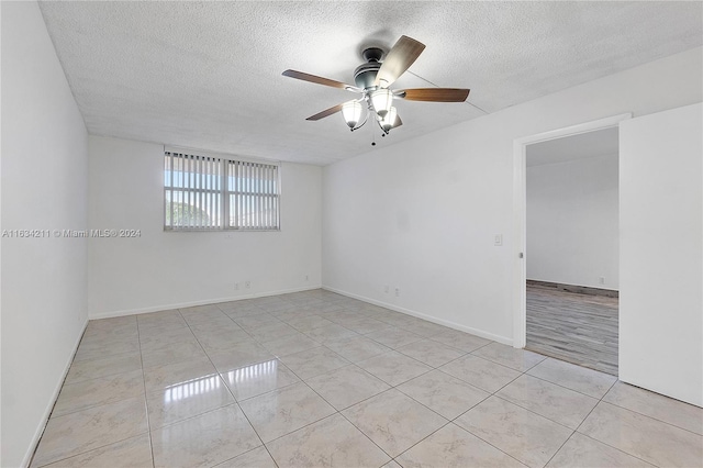 tiled spare room with a textured ceiling and ceiling fan