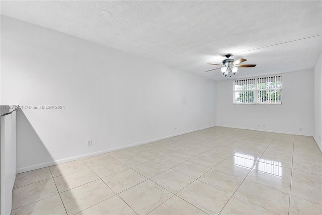 tiled empty room with a textured ceiling and ceiling fan