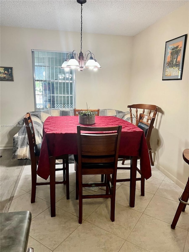 tiled dining area featuring a notable chandelier and a textured ceiling