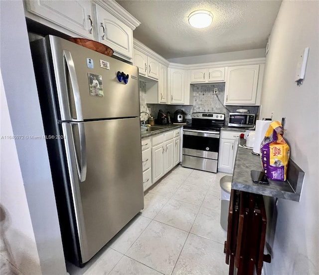 kitchen with light tile patterned floors, appliances with stainless steel finishes, backsplash, sink, and white cabinetry