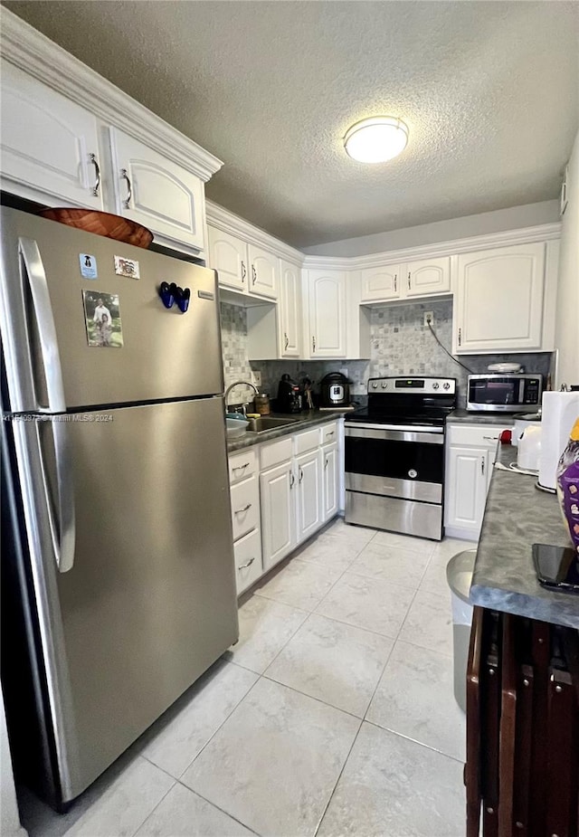 kitchen featuring appliances with stainless steel finishes, backsplash, sink, and white cabinetry