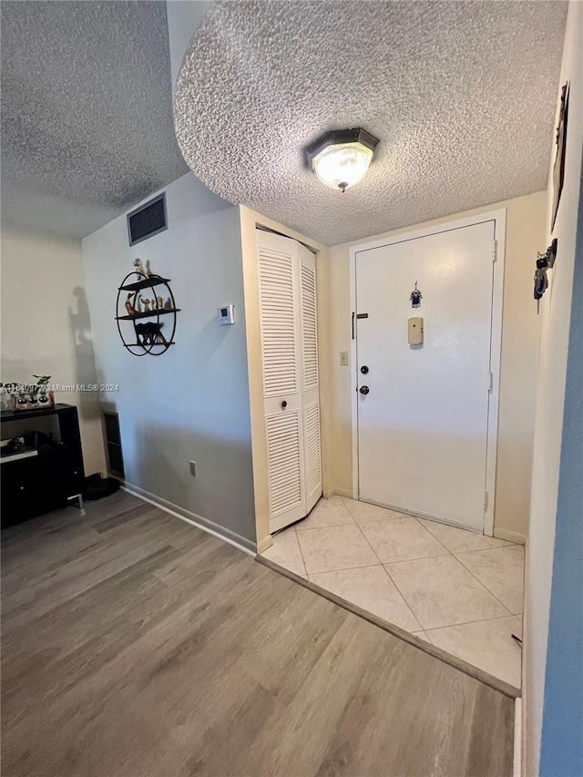 foyer with a textured ceiling and light hardwood / wood-style floors