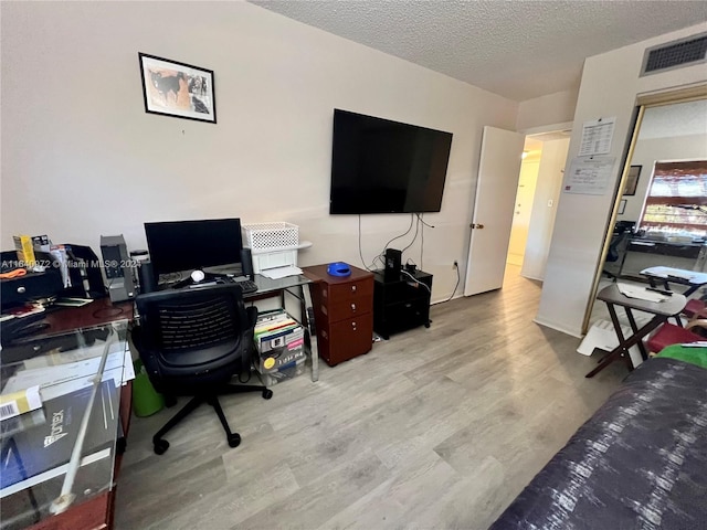 home office with light hardwood / wood-style flooring and a textured ceiling