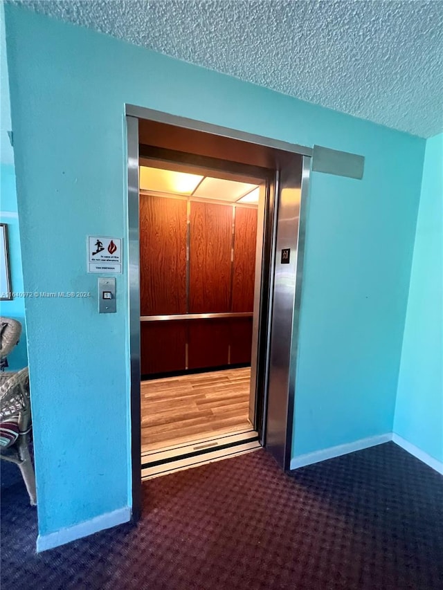 interior space with elevator, a textured ceiling, and carpet flooring