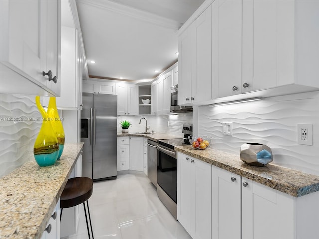 kitchen with light stone counters, stainless steel appliances, white cabinetry, light tile patterned floors, and tasteful backsplash