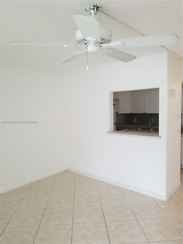 tiled empty room with ceiling fan and a textured ceiling