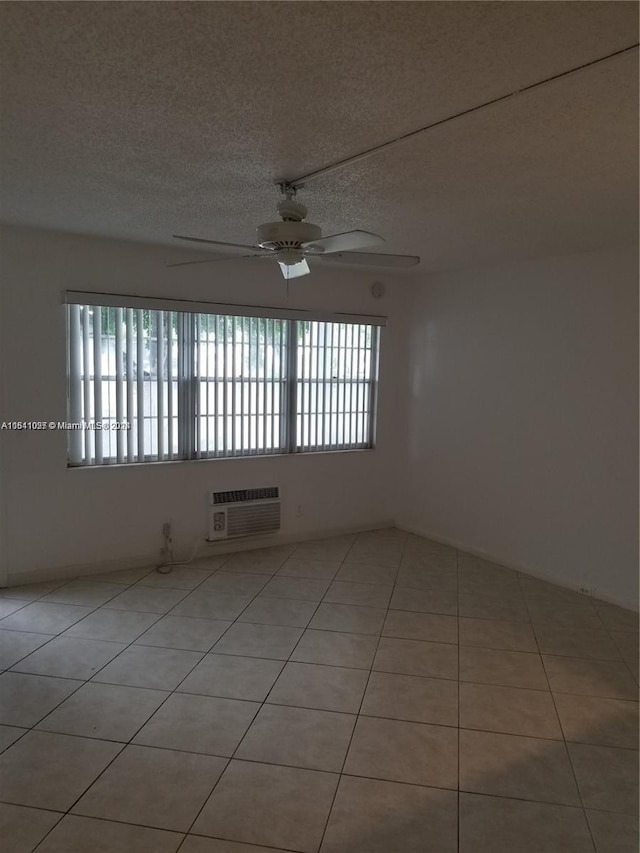 tiled spare room featuring ceiling fan, a textured ceiling, and a wall mounted AC