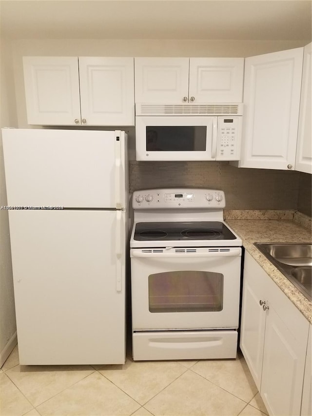 kitchen with white appliances, white cabinets, and light tile patterned floors