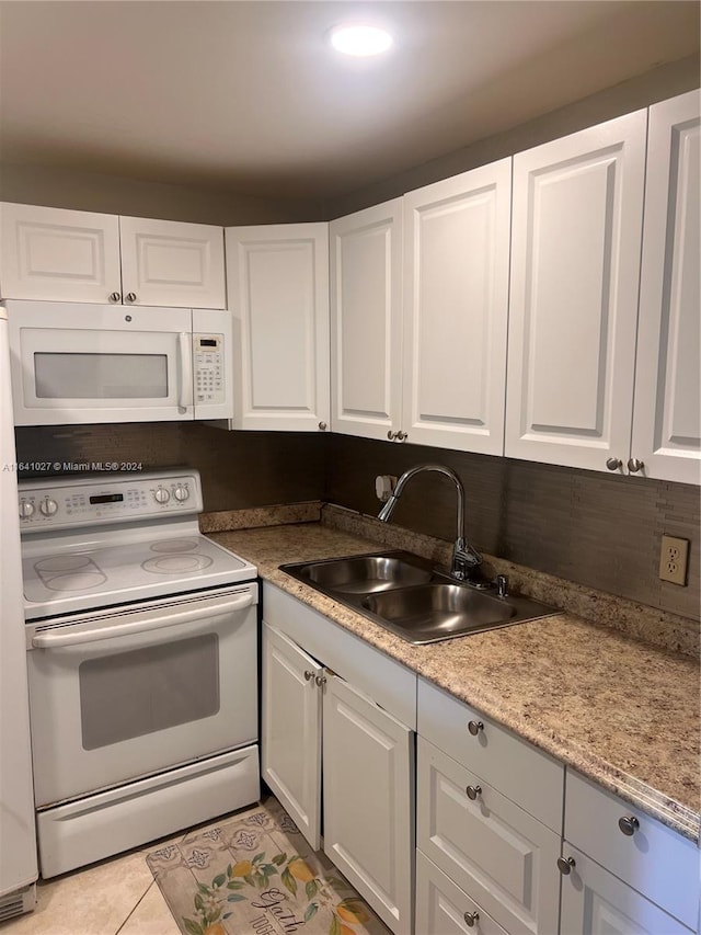 kitchen featuring sink, light stone counters, white cabinets, light tile patterned floors, and white appliances