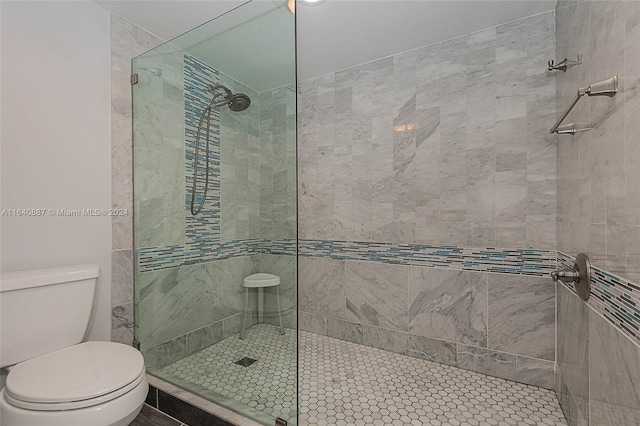 bathroom featuring a shower with shower door and toilet