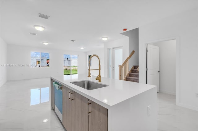 kitchen with stainless steel dishwasher, light tile patterned flooring, an island with sink, and sink