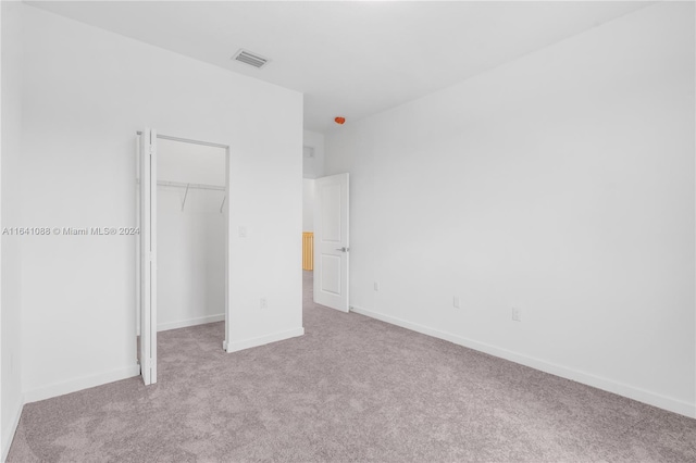 unfurnished bedroom with light carpet and a closet