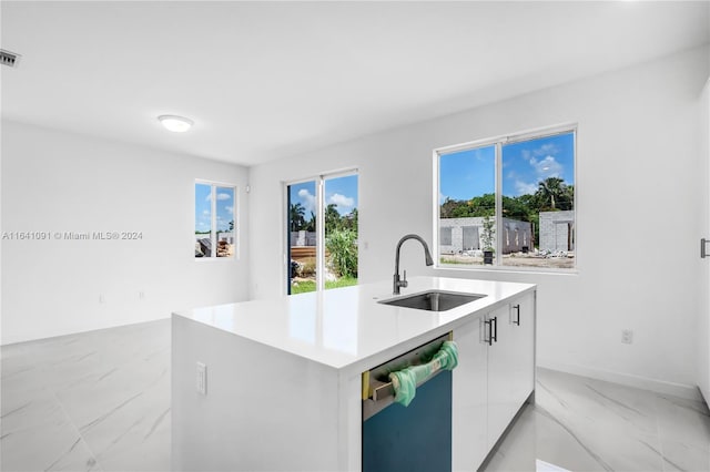 kitchen with light tile patterned flooring, white cabinets, a kitchen island with sink, and sink