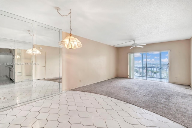 carpeted spare room featuring ceiling fan and a textured ceiling