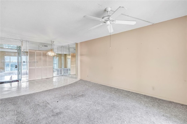 spare room featuring floor to ceiling windows, ceiling fan, and carpet