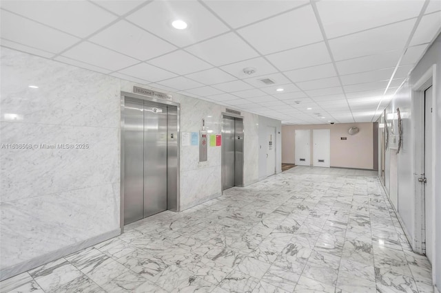 corridor with elevator and a drop ceiling