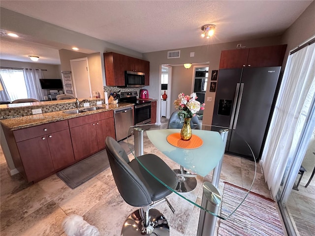 kitchen featuring a textured ceiling, light stone counters, sink, and stainless steel appliances