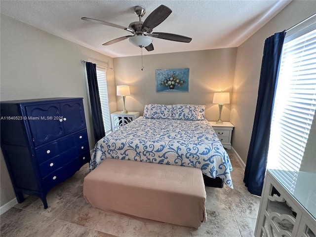 bedroom with ceiling fan, a textured ceiling, and multiple windows