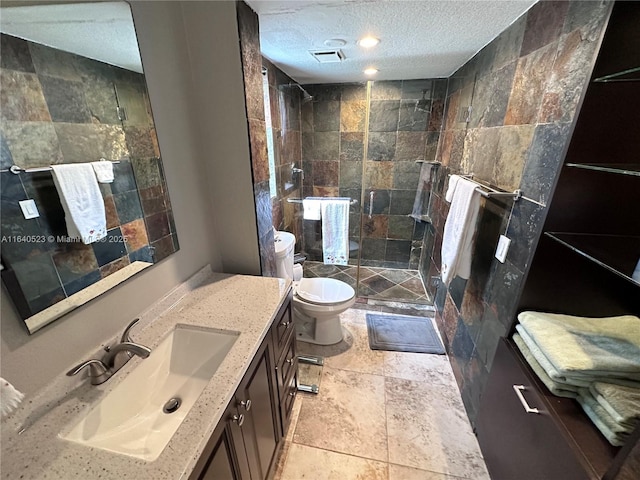 bathroom featuring vanity, a tile shower, a textured ceiling, and toilet