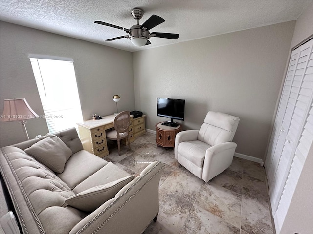 living room with a textured ceiling and ceiling fan