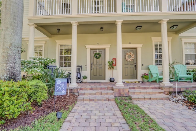 view of exterior entry with a balcony and covered porch