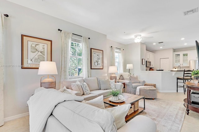 living room featuring light tile patterned flooring, sink, and ceiling fan