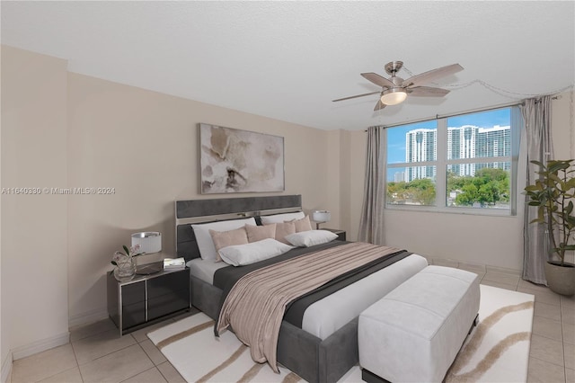 bedroom with a textured ceiling, light tile patterned floors, and ceiling fan