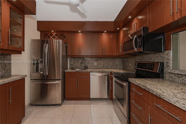 kitchen featuring sink, light tile patterned floors, appliances with stainless steel finishes, light stone counters, and tasteful backsplash