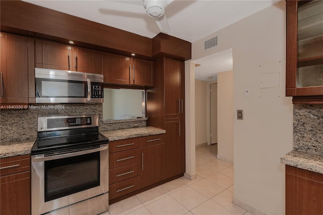 kitchen with light stone countertops, stainless steel appliances, light tile patterned floors, and tasteful backsplash