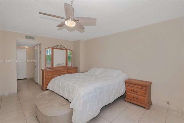 tiled bedroom with ceiling fan and a textured ceiling