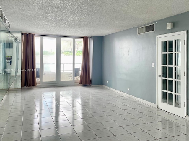 spare room with a textured ceiling and light tile patterned floors