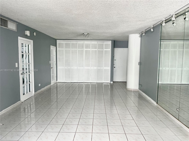 tiled empty room featuring a textured ceiling