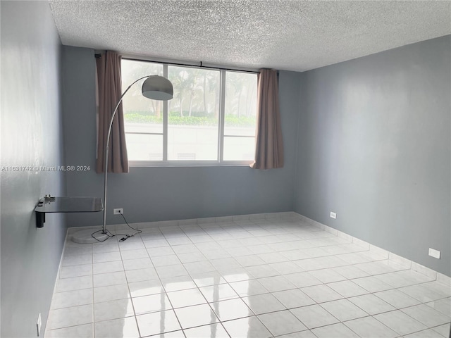 tiled empty room featuring a textured ceiling