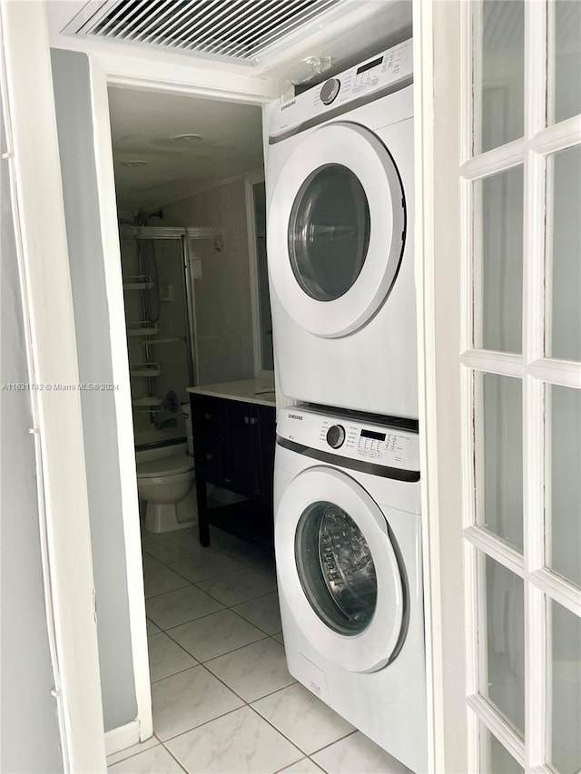 washroom featuring stacked washer and clothes dryer and light tile patterned floors