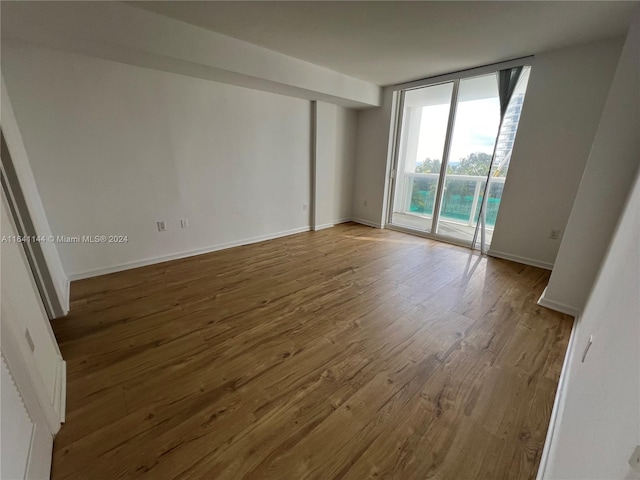 unfurnished room featuring wood-type flooring and a wall of windows