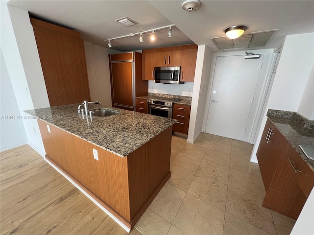 kitchen featuring sink, wall oven, track lighting, dark stone counters, and kitchen peninsula