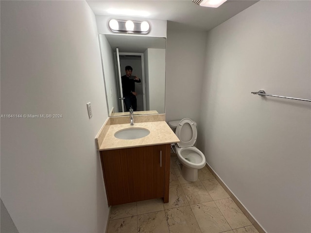 bathroom with marble finish floor, baseboards, toilet, and vanity