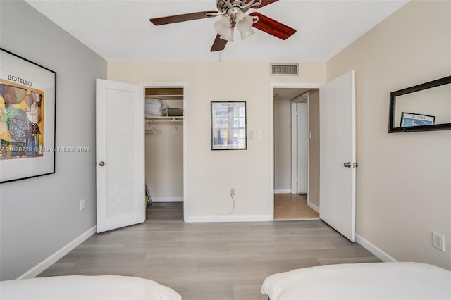 bedroom with a textured ceiling, a closet, light hardwood / wood-style floors, and ceiling fan